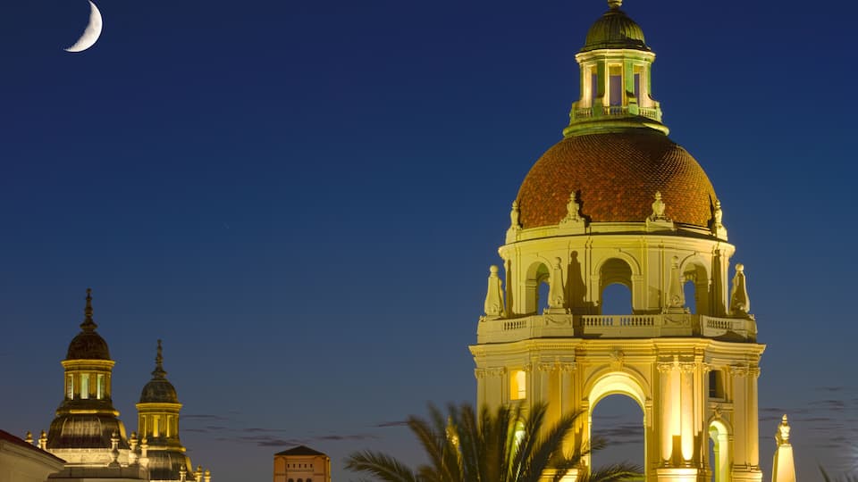 A large illuminated dome with statues, a crescent moon, and two smaller domes in the background.