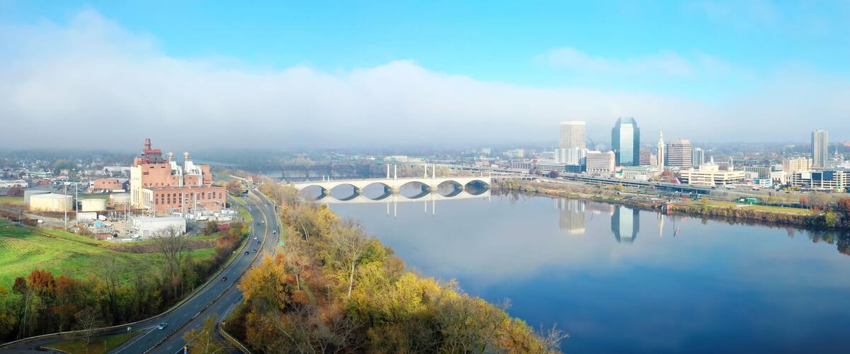 A river with a bridge, a city skyline, and a red brick building.