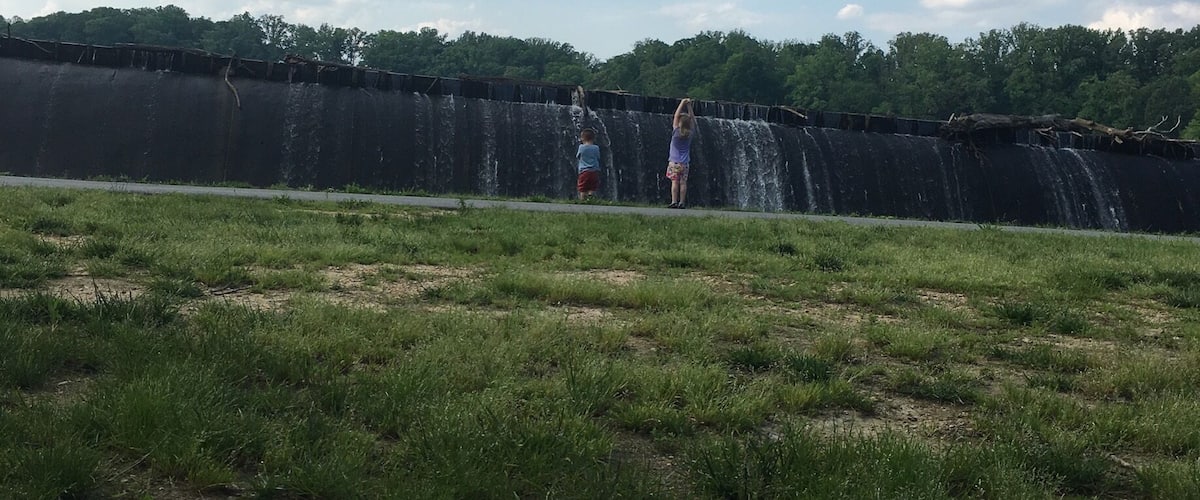 A grassy field with a large dam and a waterfall.