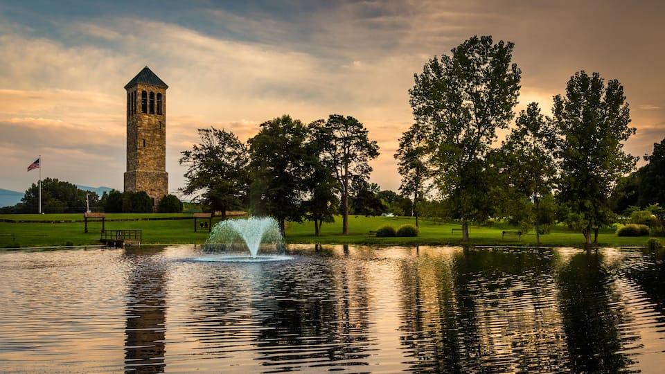 A tower, a fountain, and trees in a park.
