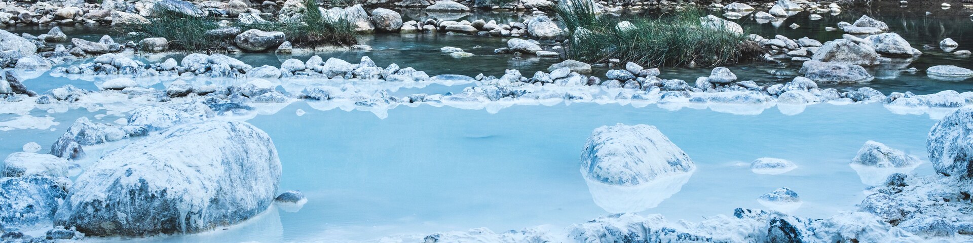 Un río de aguas cristalinas, rodeado de rocas y exuberante follaje verde.