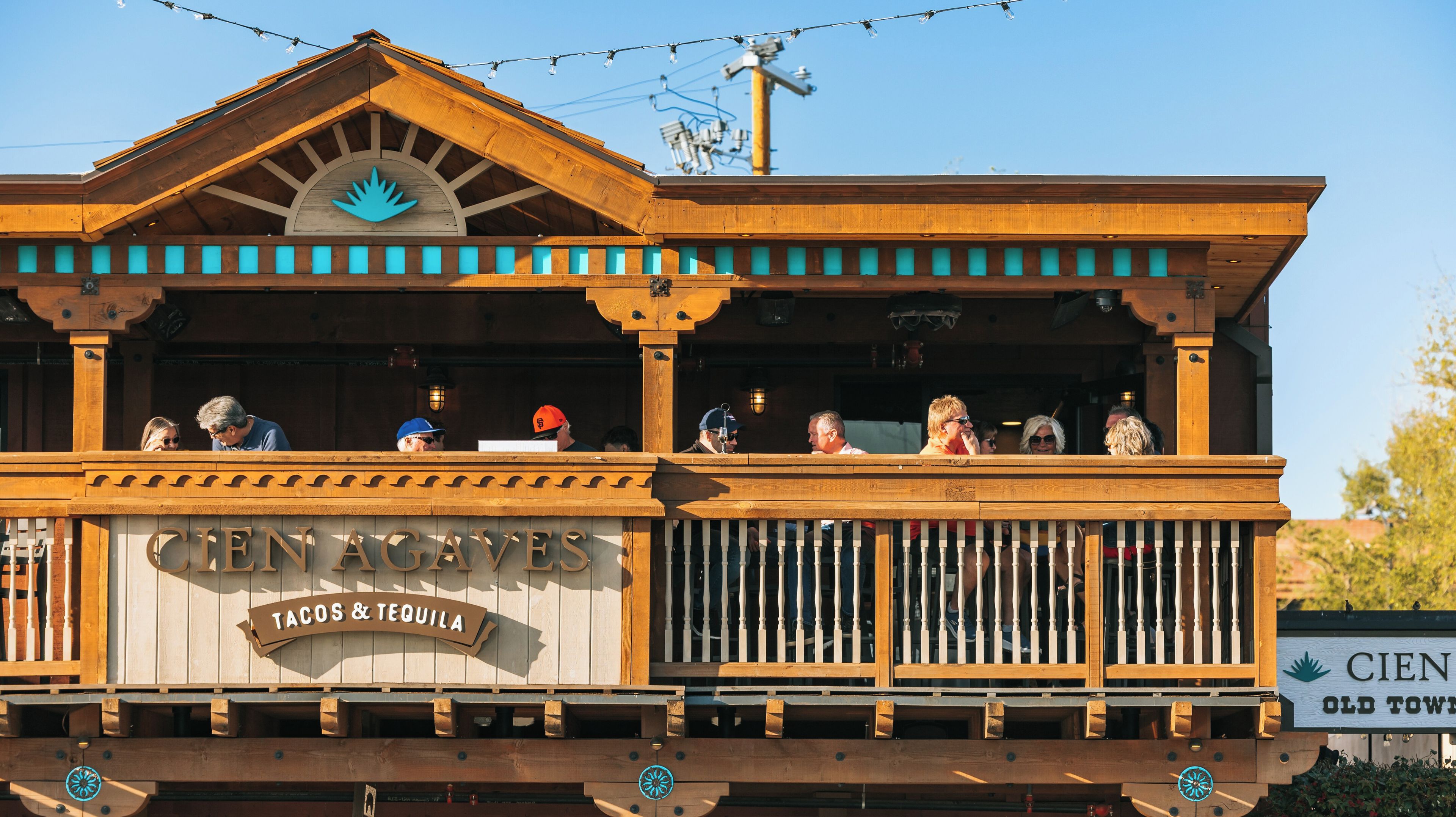 A wooden building with a sign reading 'CIEN AGAVES Tacos & Tequila.'