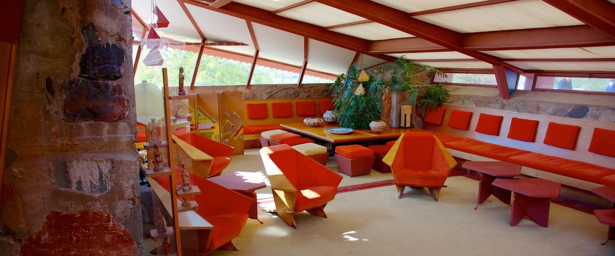 A modern interior with orange and red furniture, a stone wall, and a wooden ceiling.