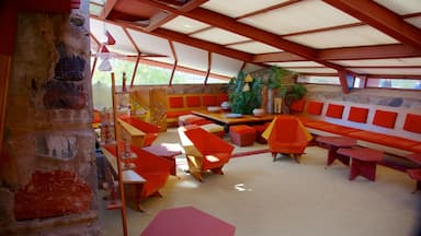 Um interior moderno com móveis laranja e vermelhos, uma parede de pedra e teto de madeira.