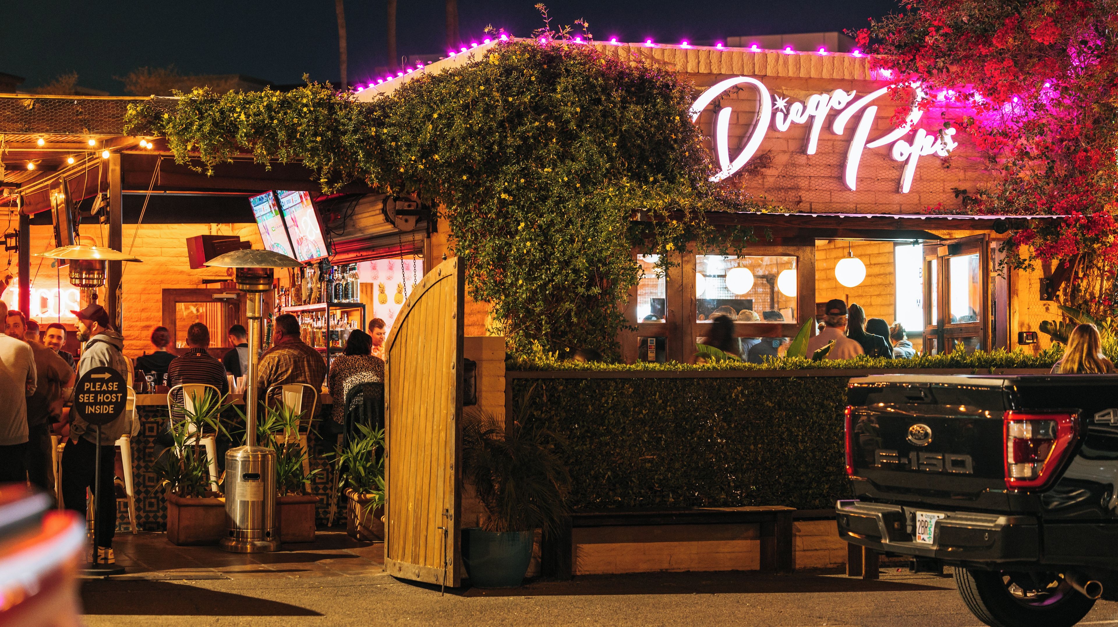 A brightly lit restaurant named 'Diego's Hope' with outdoor seating and a neon sign.
