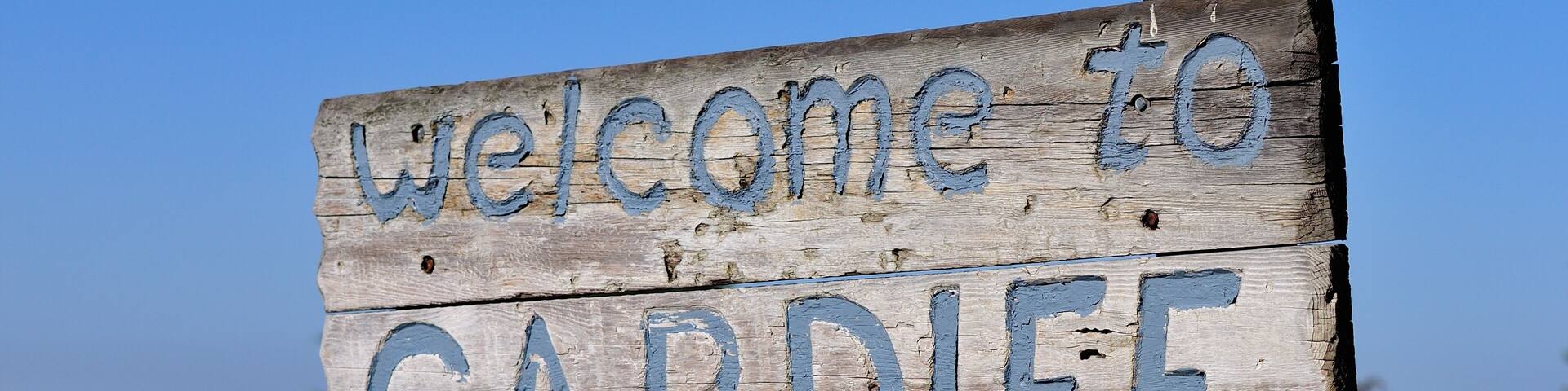 A wooden sign with 'Welcome to CARDIFF By the Sea' written on it.