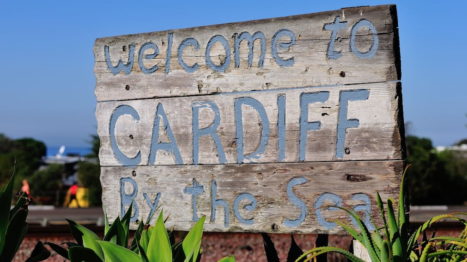 A wooden sign with 'Welcome to CARDIFF By the Sea' written on it.