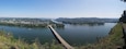 A river with a bridge, surrounded by greenery and hills.