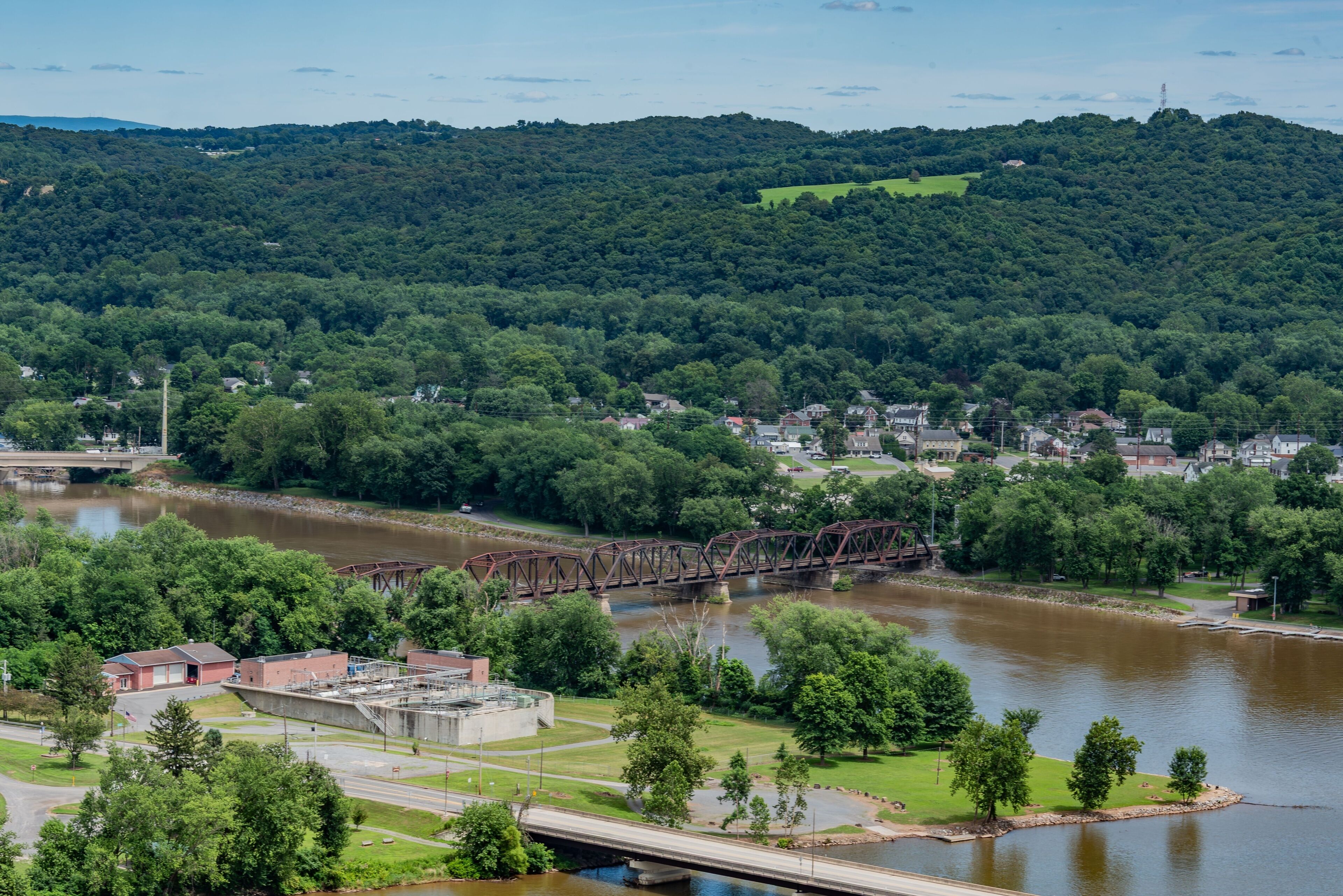 A river with a bridge, surrounded by greenery and a town.