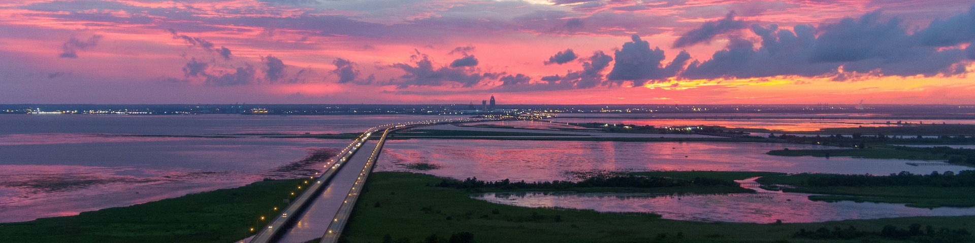 A sunset over a coastal highway with water on either side.