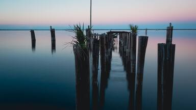 Old historic dock posts in Lake Monroe at downtown Sanford Riverwalk in Florida at sunset