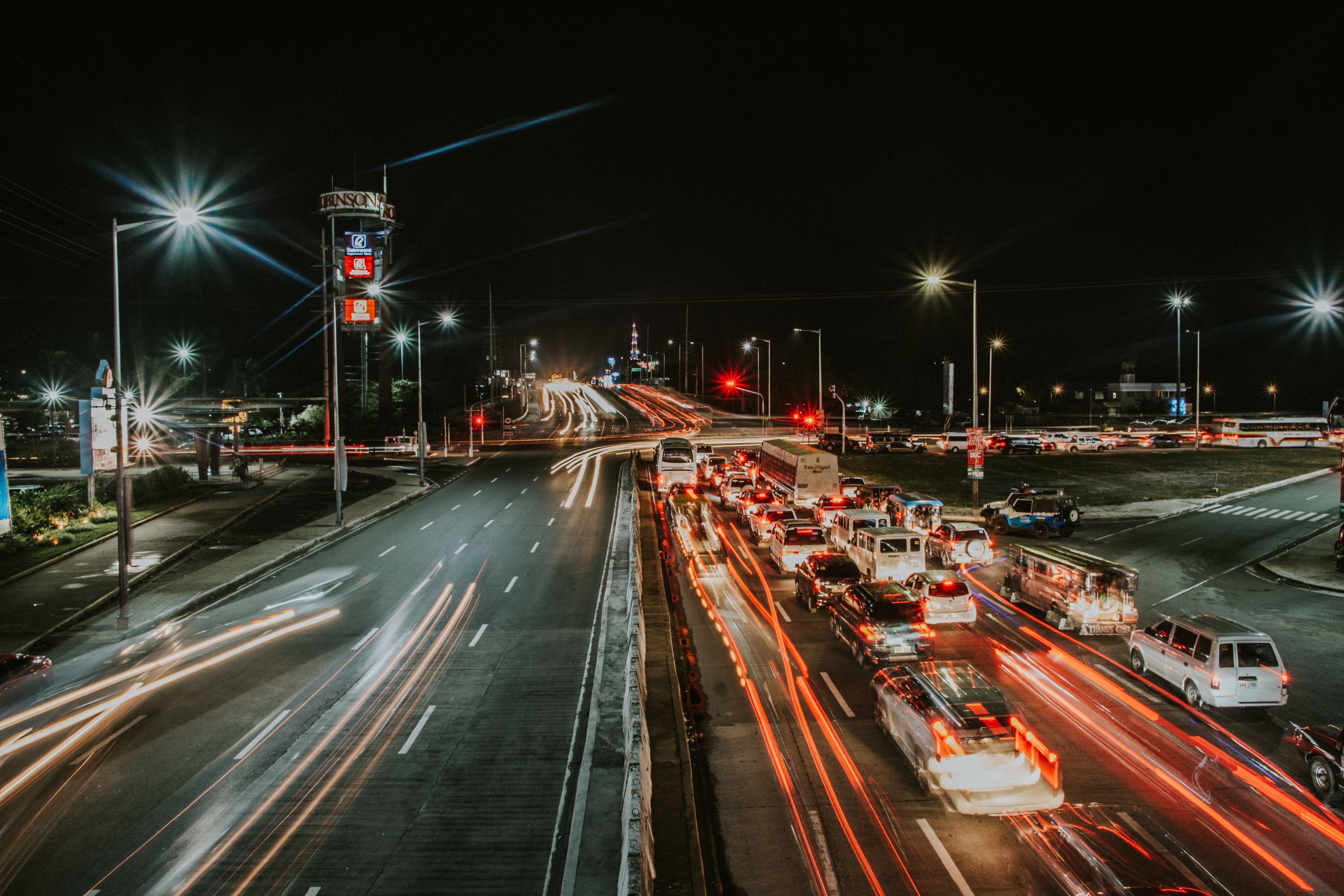 A nighttime cityscape with a busy intersection, illuminated signs, and a prominent tower.
