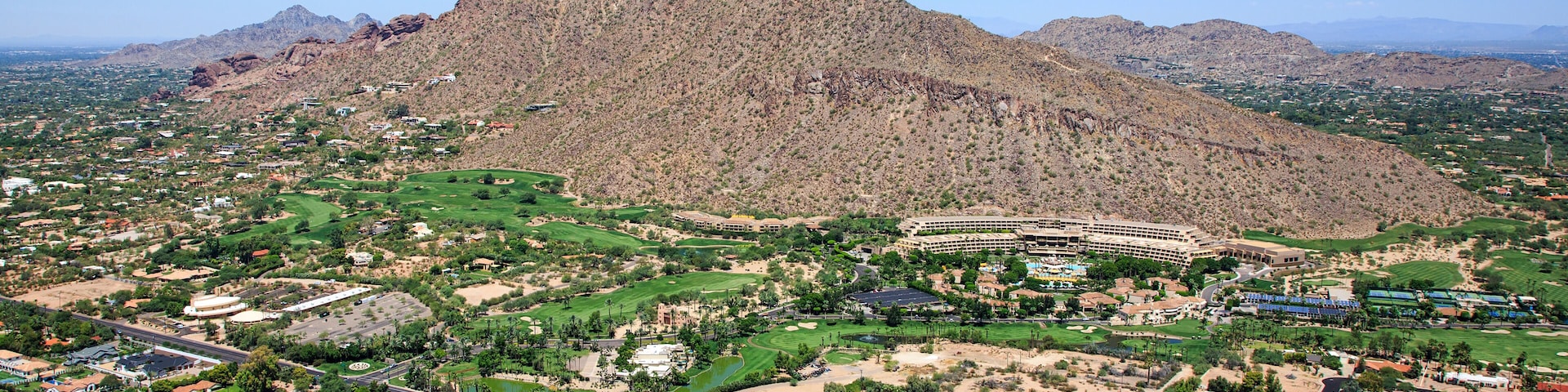 Eine gebirgige Landschaft mit einem Golfplatz und Wohngebieten.