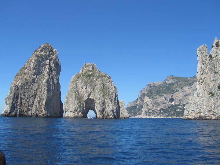 Isle of Capri day trip - apparently these are the Faraglioni: the three spurs of rock which rise up out of the sea. It's just off the coast of the Isle of Capri and as part of the grotto tour you go through the hole in the middle. The water is a clear and a beautiful green-blue.