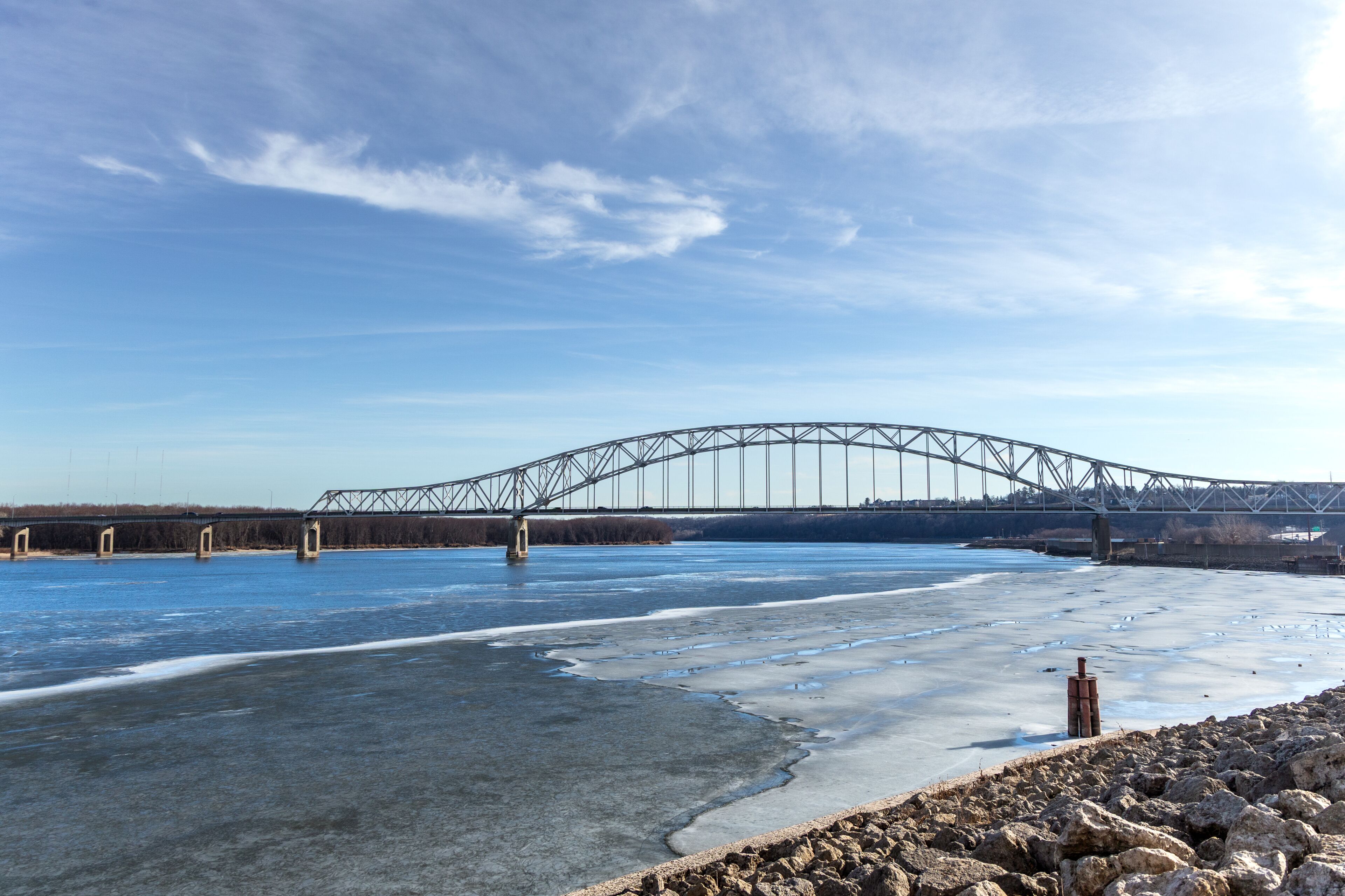 A large steel bridge over a frozen river with clear skies.
