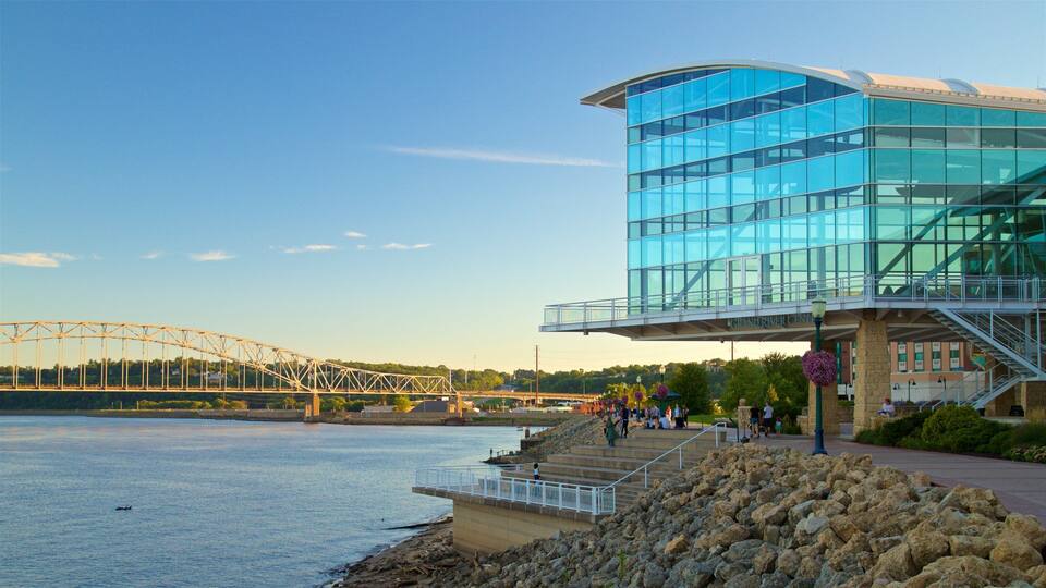A modern glass building with a bridge in the background.