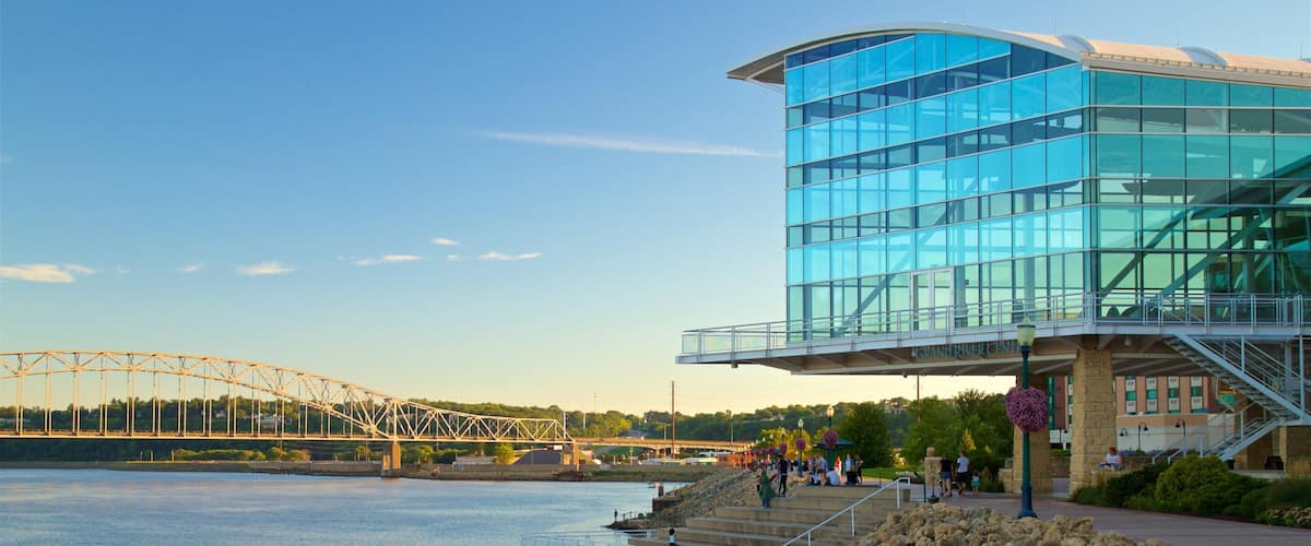 A modern glass building with a bridge in the background.