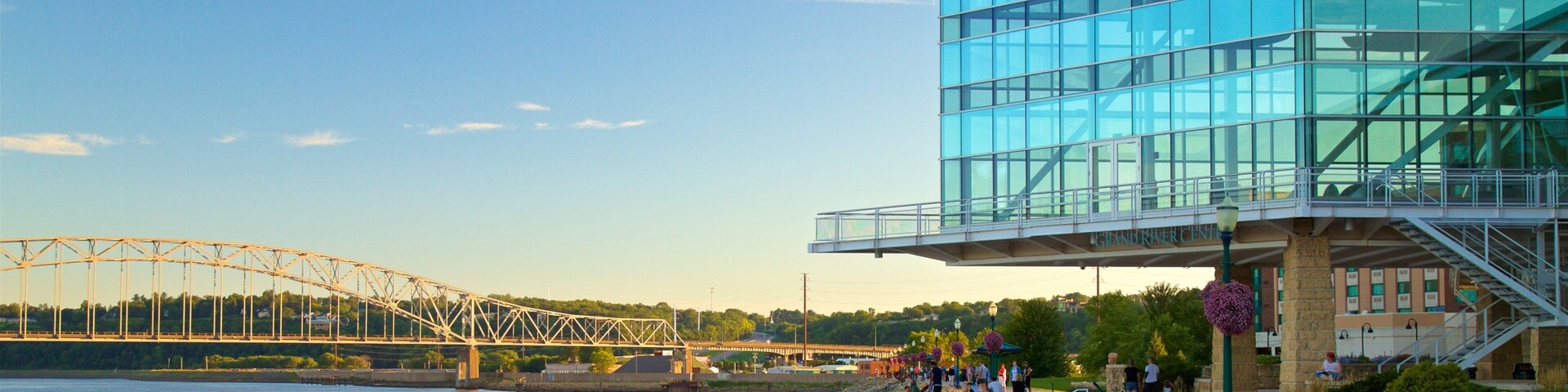 A modern glass building with a bridge in the background.