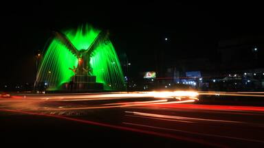 Light trails of vehicles and traffic around an illuminated monument of Sargodha with a showering fountain. It's a long exposure shoot of 30 seconds with selective focus.