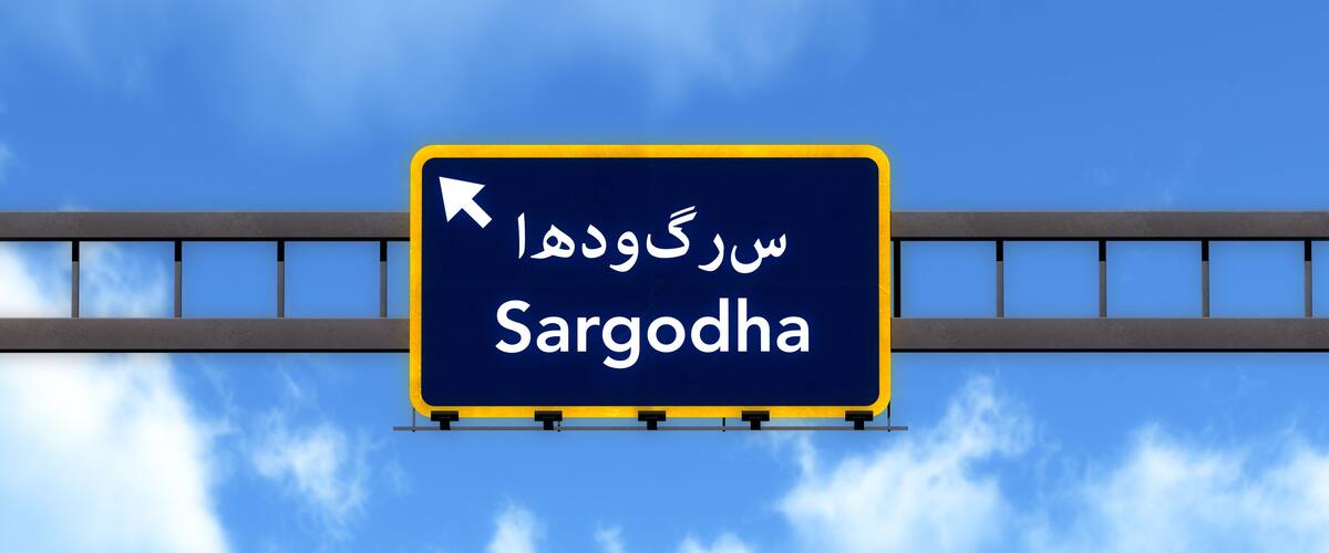 A road sign with the text 'Sargodha' and an arrow pointing left.