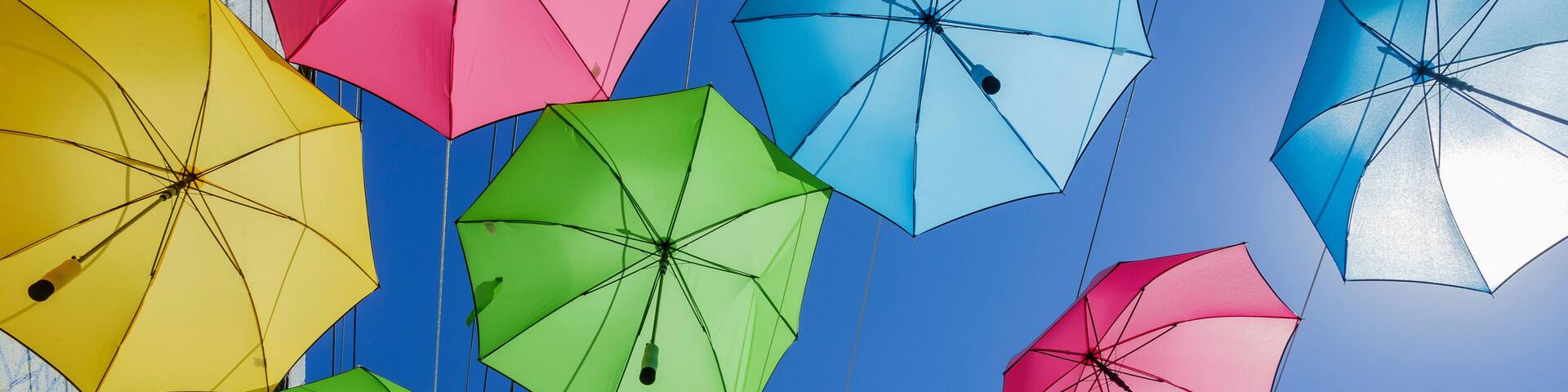 A collection of colorful umbrellas against a clear blue sky.