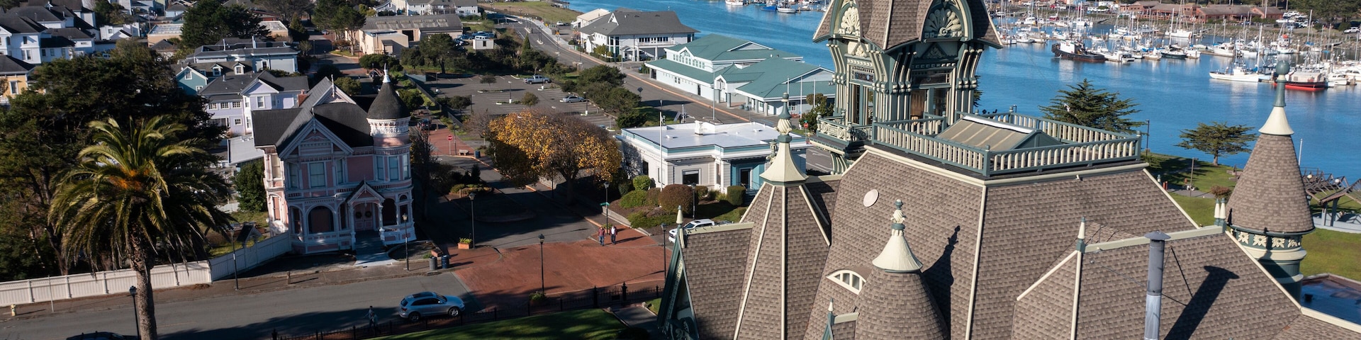 A coastal town with a prominent church steeple, a marina with boats, and a bridge in the distance.