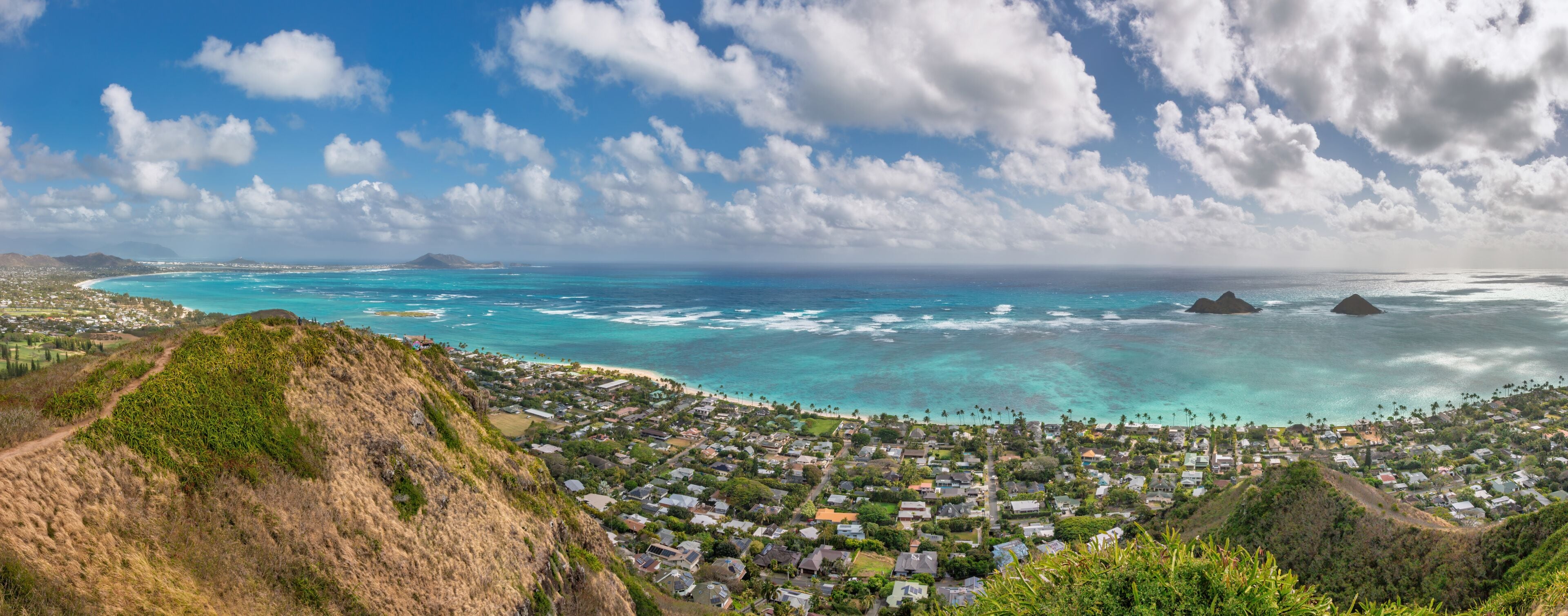 Panoramic view of famous Lanikai Beach and Kailua Bay on the island of Oahu, Hawaii, USA with Mokulua Islands or Twin Islands against blue sky with clouds