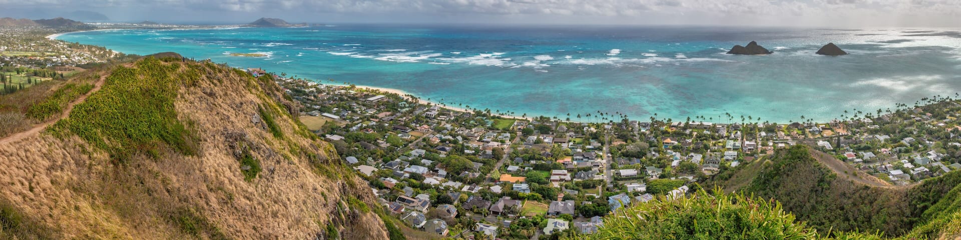 Panoramic view of famous Lanikai Beach and Kailua Bay on the island of Oahu, Hawaii, USA with Mokulua Islands or Twin Islands against blue sky with clouds
