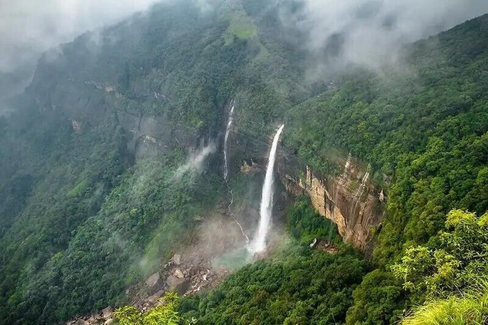 A waterfall cascading down a lush, green mountain.