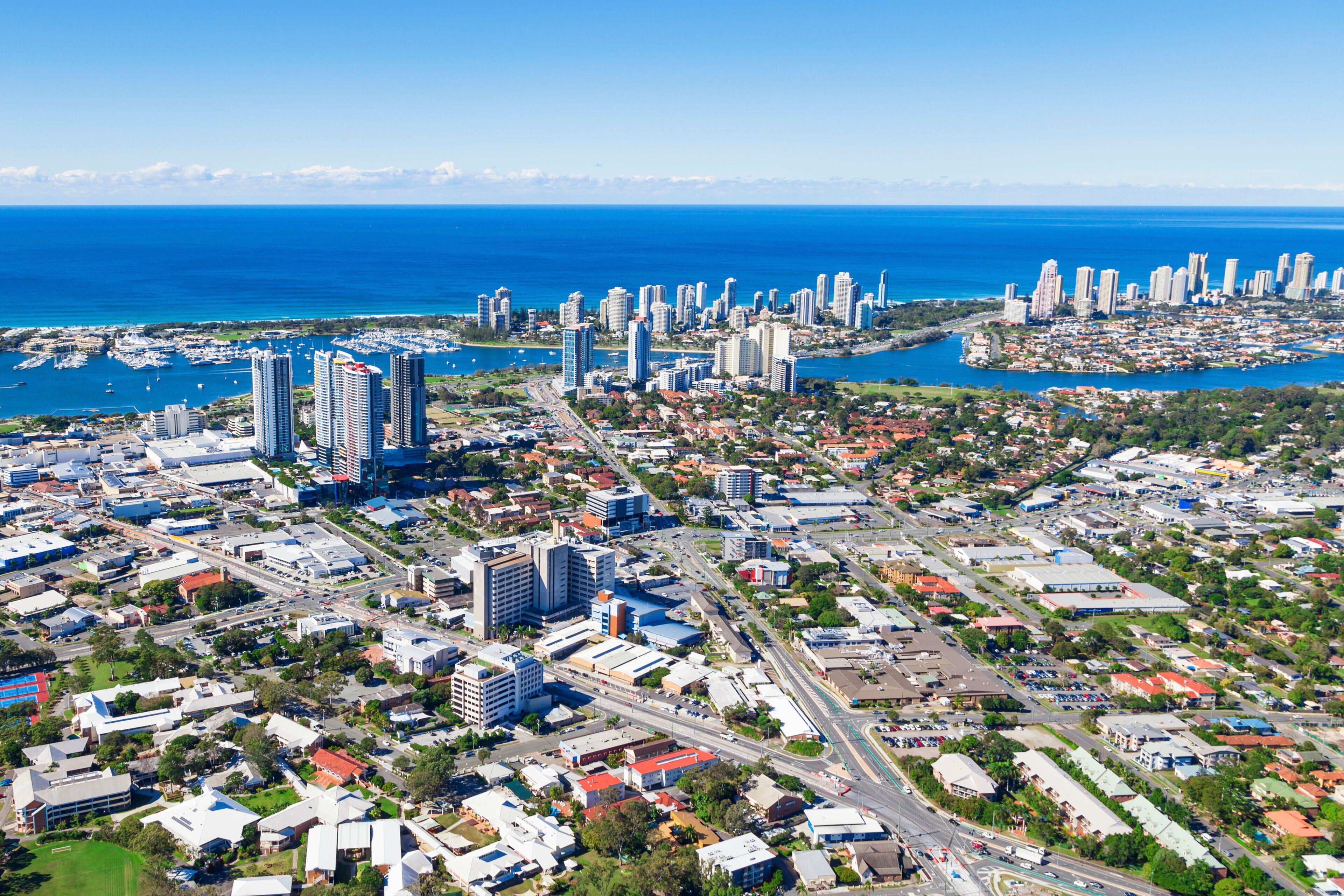 A coastal cityscape with high-rise buildings, a marina, and a clear blue sky.