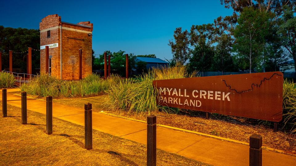 A sign for Myall Creek Parkland with a brick structure in the background.