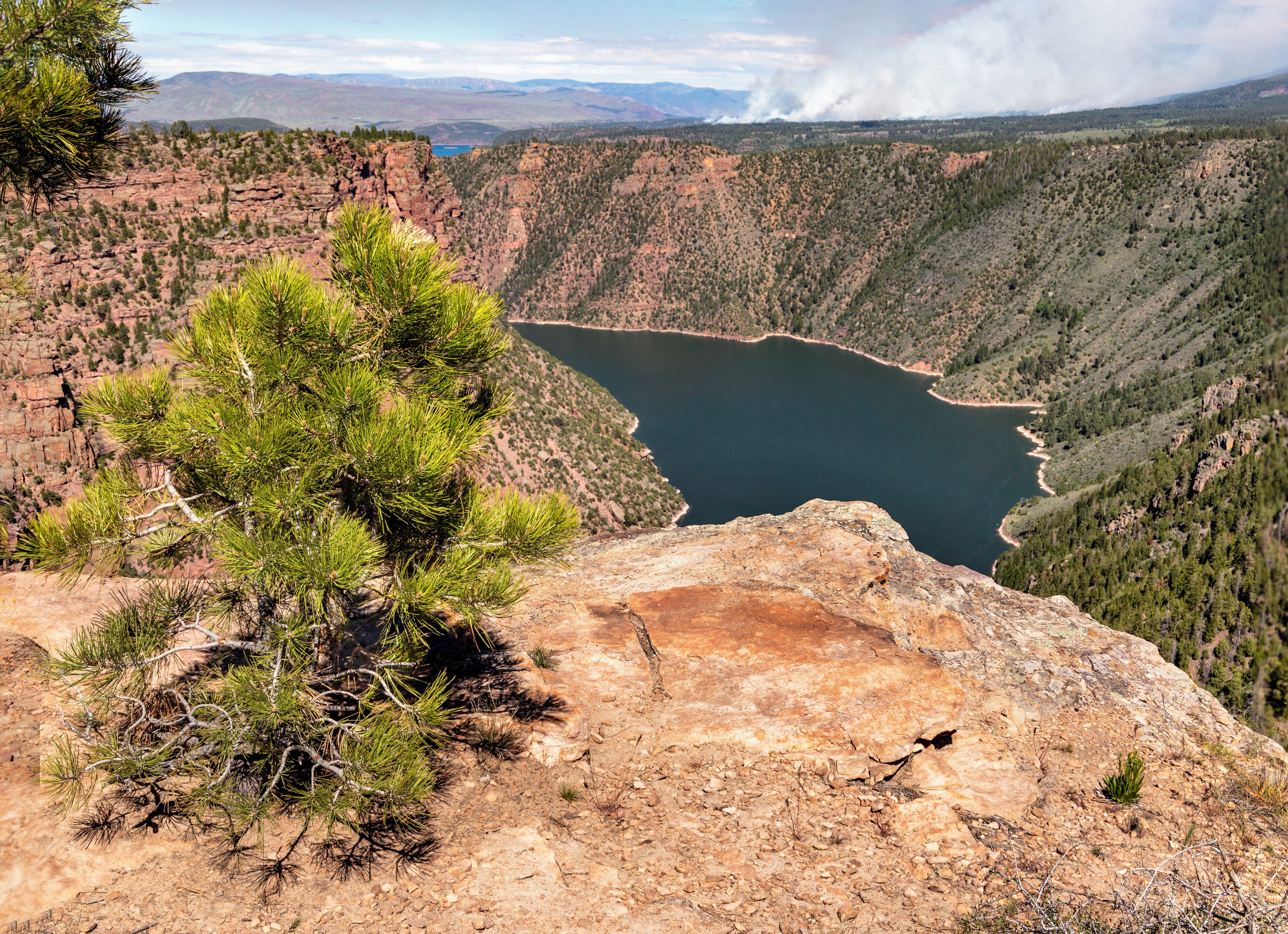 We passed this spot near Flaming Gorge as we drove from Jackson WY to Vernal Utah as part of a road trip. In the distance a forest fire can be seen. It turned out to be part of a controlled burn. This area is beautiful but care is needed as there are a lot of drop offs and deep cracks in the cliffs to get over. 