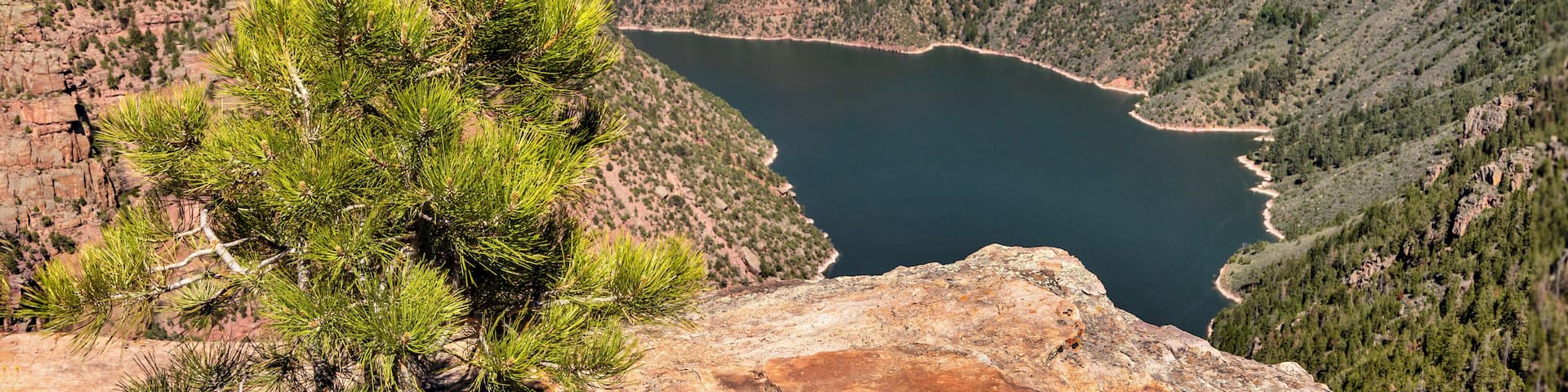 A canyon with a lake, surrounded by rocky terrain and sparse vegetation.