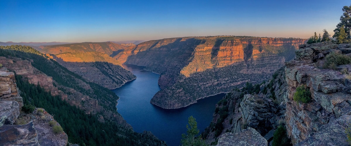 A canyon with a river, steep cliffs, and sparse vegetation.