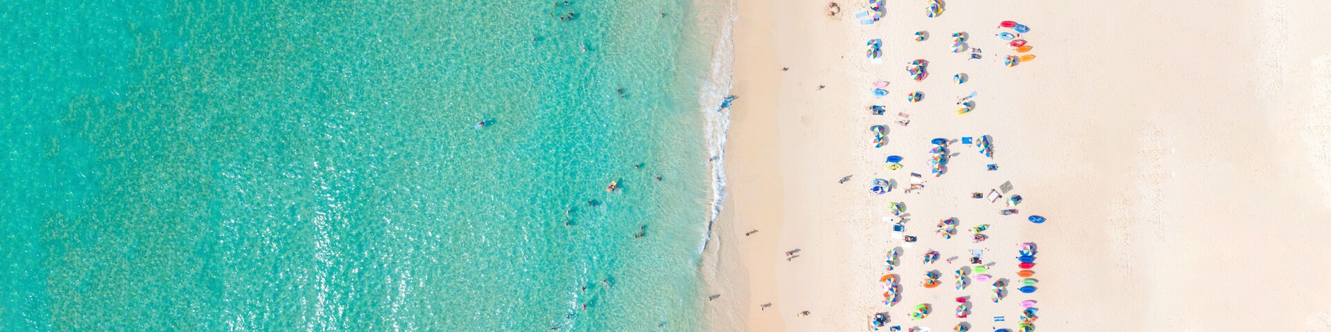 A beach with clear turquoise water and a sandy shore.