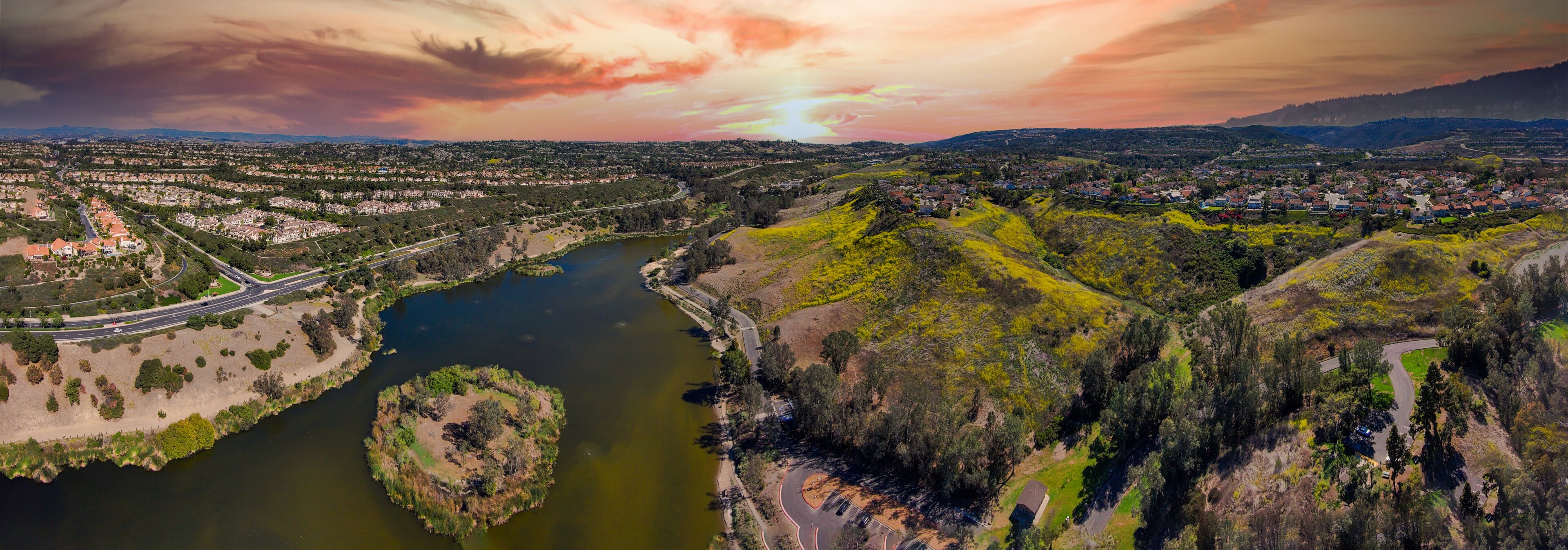 A river winding through a valley with a town on the right and a highway on the left.