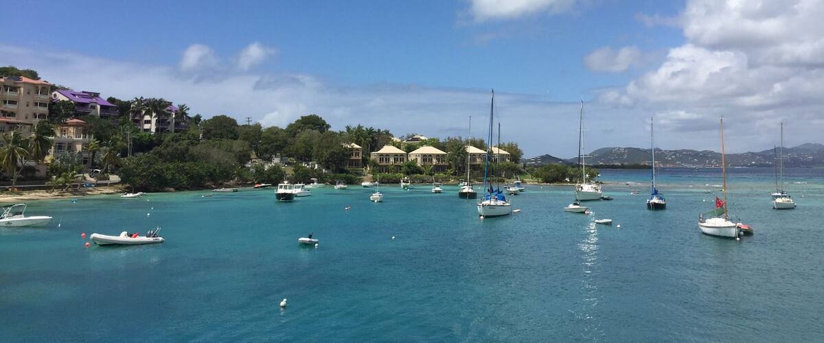 A coastal town with clear turquoise waters, numerous sailboats, and buildings with purple roofs.