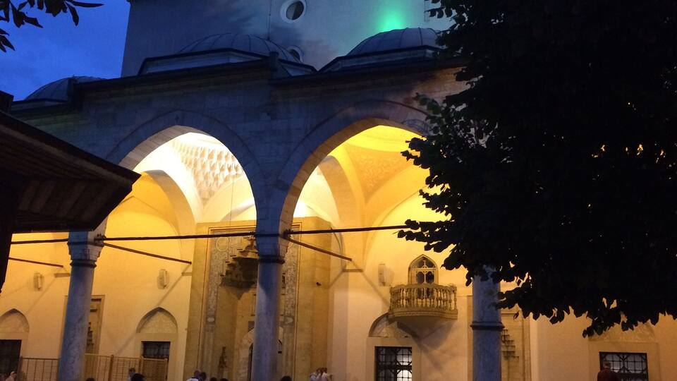 Un edificio histórico con arcos y columnas, iluminado al anochecer.