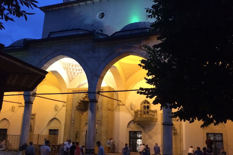 A historic building with arches and columns, illuminated at dusk.