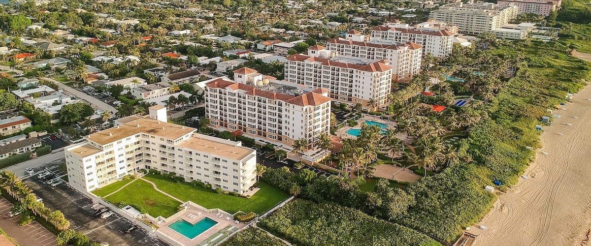 Una zona residencial costera con propiedades frente al mar, un puerto deportivo y un puente a lo lejos.