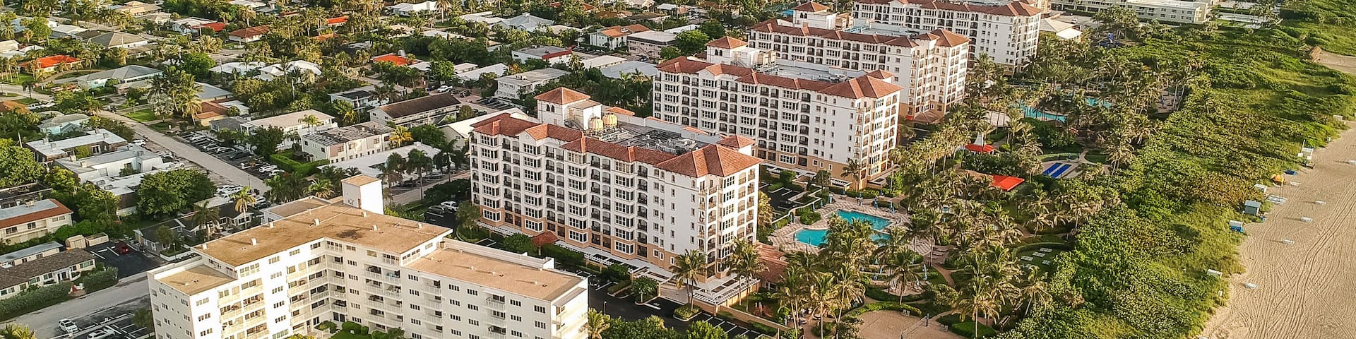 A coastal residential area with beachfront properties, a marina, and a bridge in the distance.
