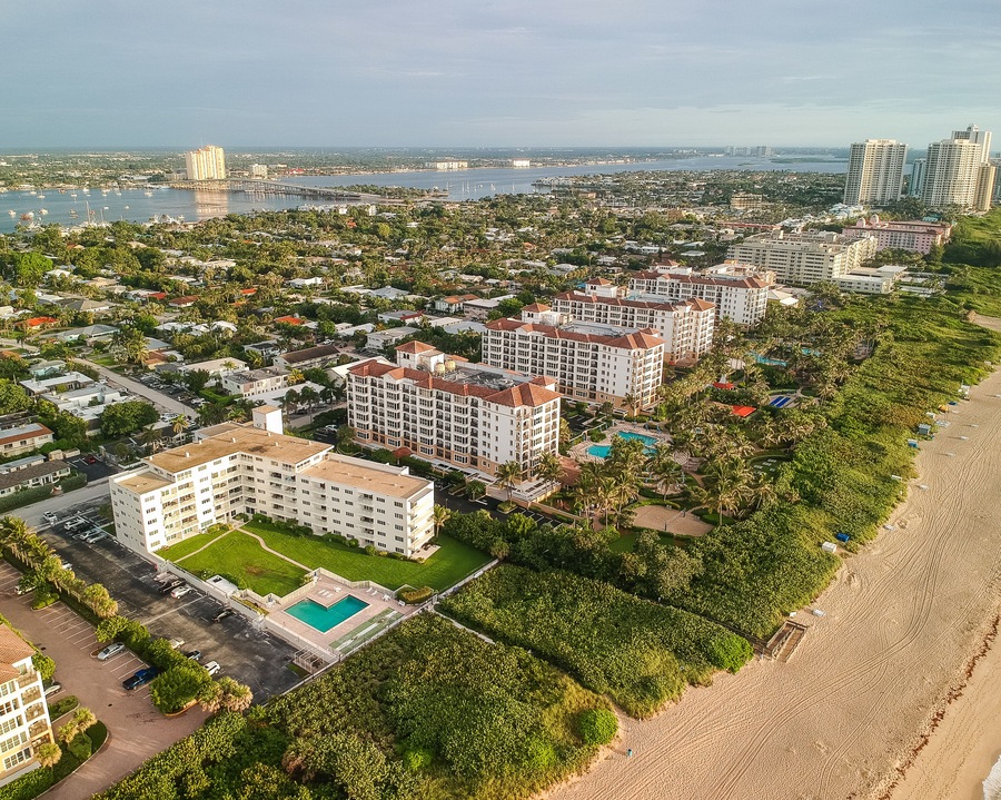 A coastal residential area with beachfront properties, a marina, and a bridge in the distance.