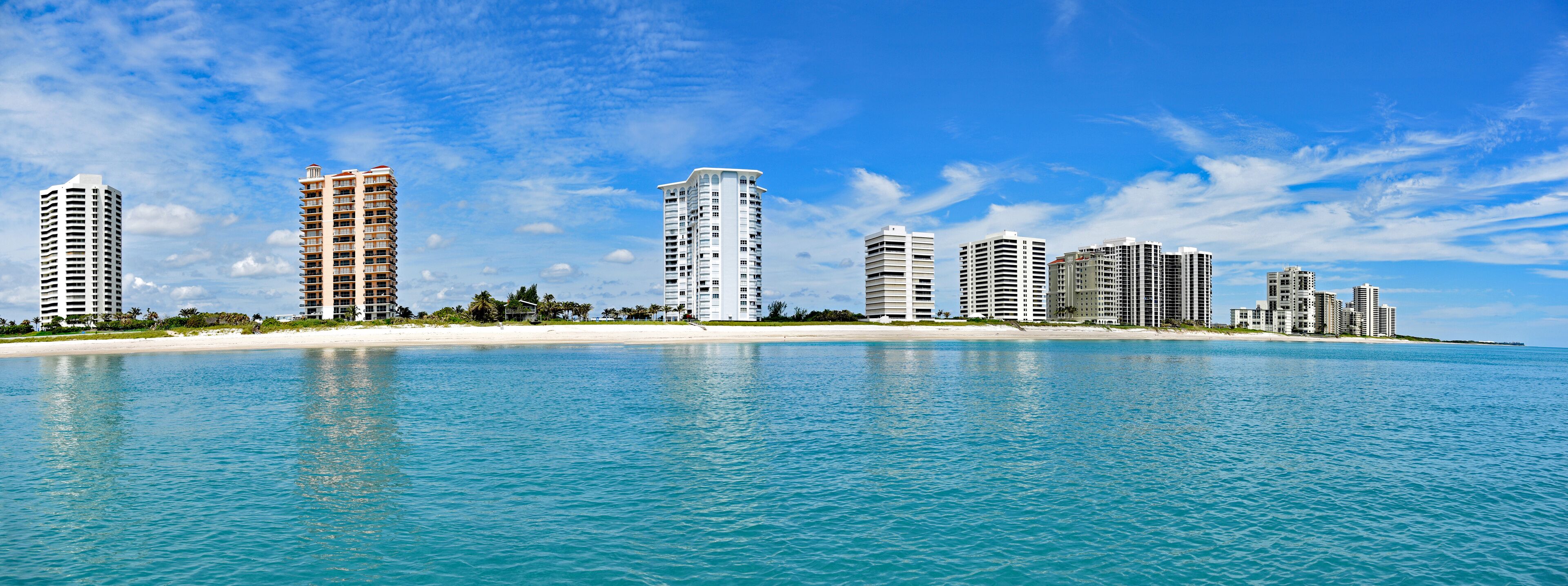 A coastal cityscape with high-rise buildings and a sandy beach.