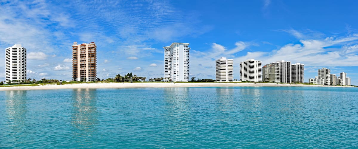 A coastal cityscape with high-rise buildings and a sandy beach.