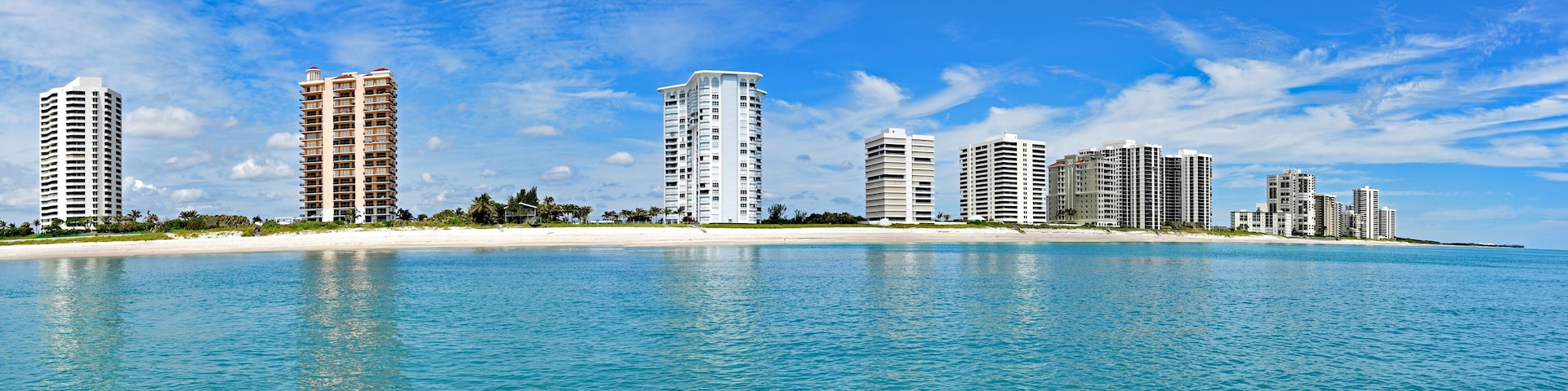 A coastal cityscape with high-rise buildings and a sandy beach.