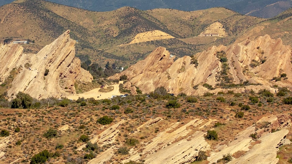 A rugged desert landscape with prominent rock formations and sparse vegetation.