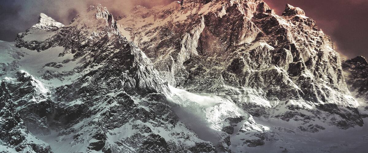 A snow-covered mountain range with sharp peaks and a glacier.