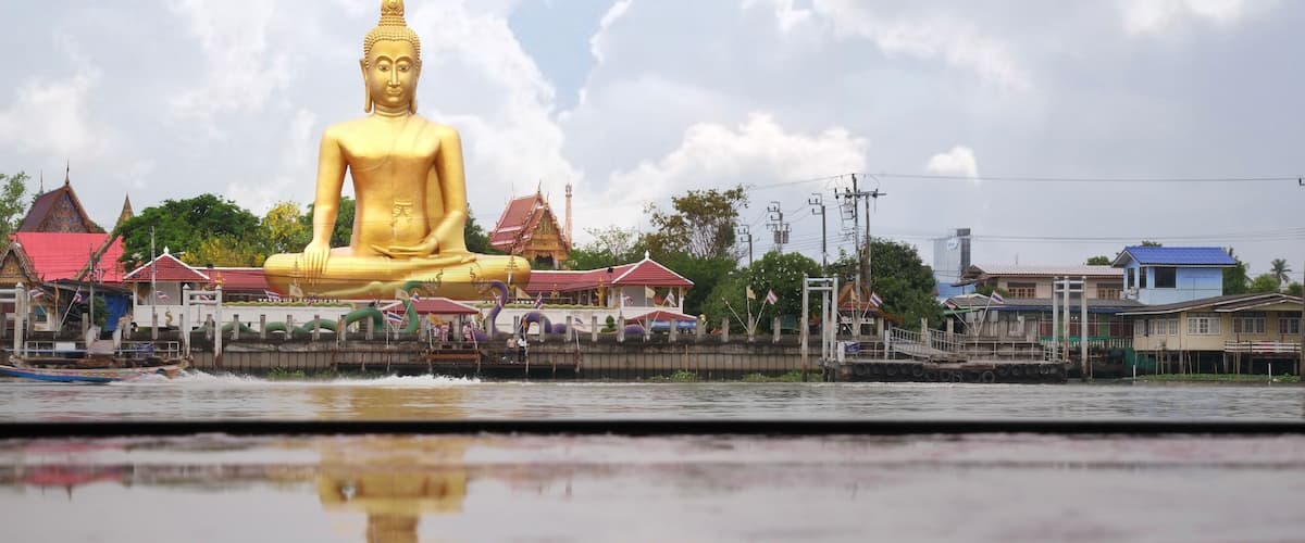 April 6 2021 - Nonthaburi, Thailand : Big golden buddha statue with reflection on wet table at Wat Bangjak located by the Chao Phraya River, Thailand
