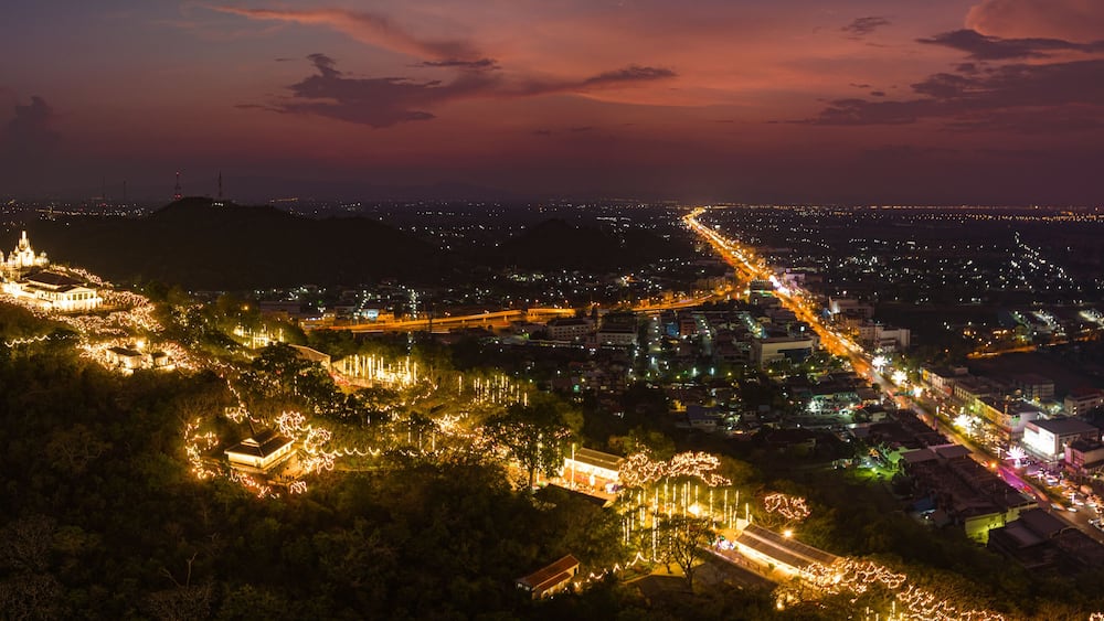 A stunning display of golden fireworks lights up the night sky above an illuminated hilltop palace. The vibrant celebration contrasts beautifully with the dark sky, Phetchaburi festival firework.