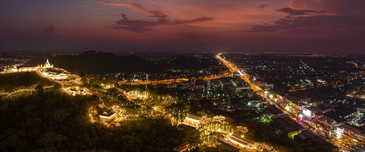 A cityscape at night with illuminated streets and a prominent hilltop structure.
